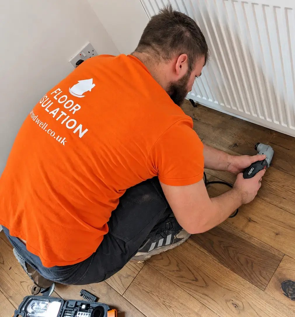 A Warmdwell specialist carefully creating access through a wooden floor